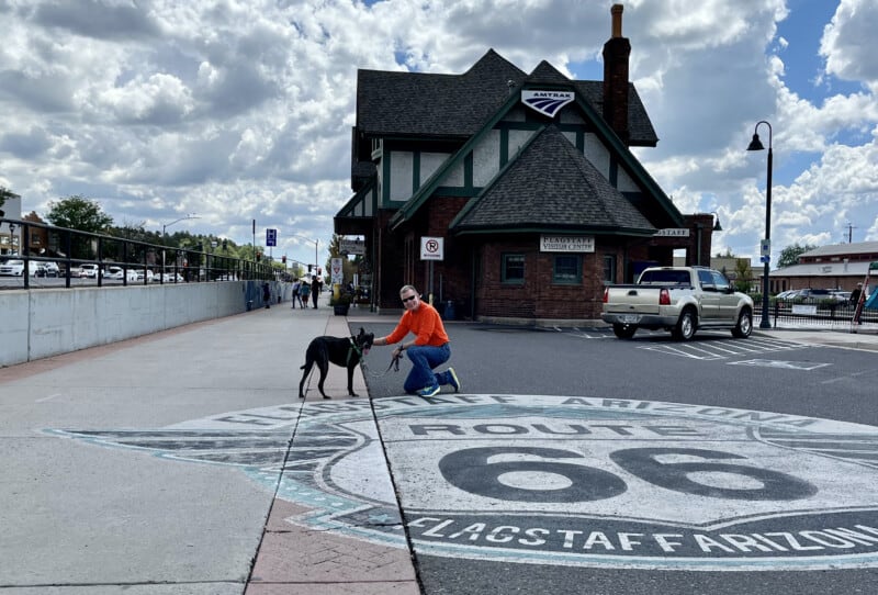 Man and a dog on the Route 66 sign painted on the parking lot at the Visitor Center in Flagstaff, AZ